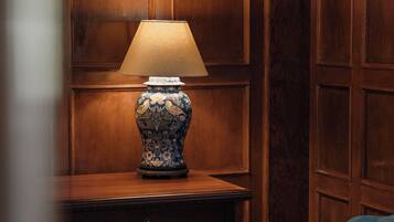 A wooden paneled wall, a table with a lamp, and a blue chair.