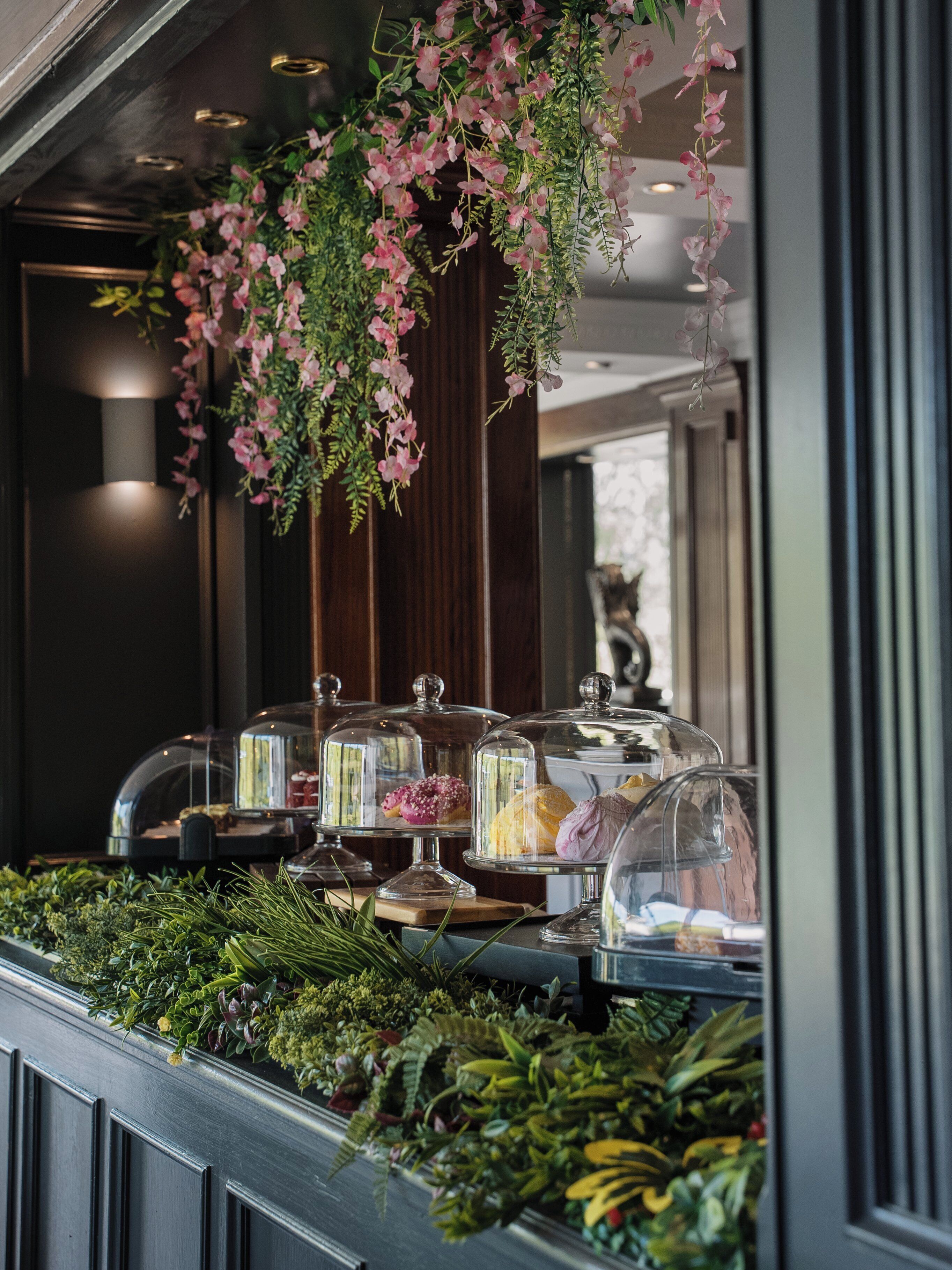 A buffet area with glass-covered food displays and hanging floral arrangements.