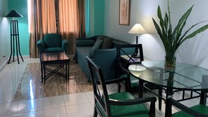 A modern living room with a sofa, armchairs, a coffee table, and a dining table with chairs. - The Pearl Manila Hotel (Manila)