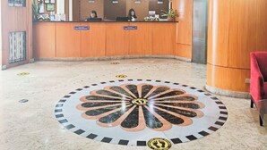 A hotel reception area with a marble floor, a reception desk, a chandelier, and a red chair. - The Pearl Manila Hotel (Manila)