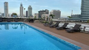 A rooftop pool with lounge chairs and a city skyline in the background. - The Pearl Manila Hotel (Manila)