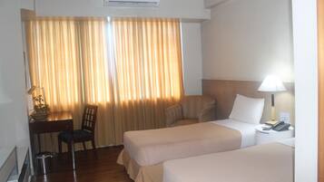 Habitación de hotel con dos camas, un escritorio, una silla, una lámpara y un teléfono.