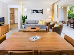Ein modernes Wohnzimmer mit einer Couch, Sesseln, einem Couchtisch und einem Fernseher.