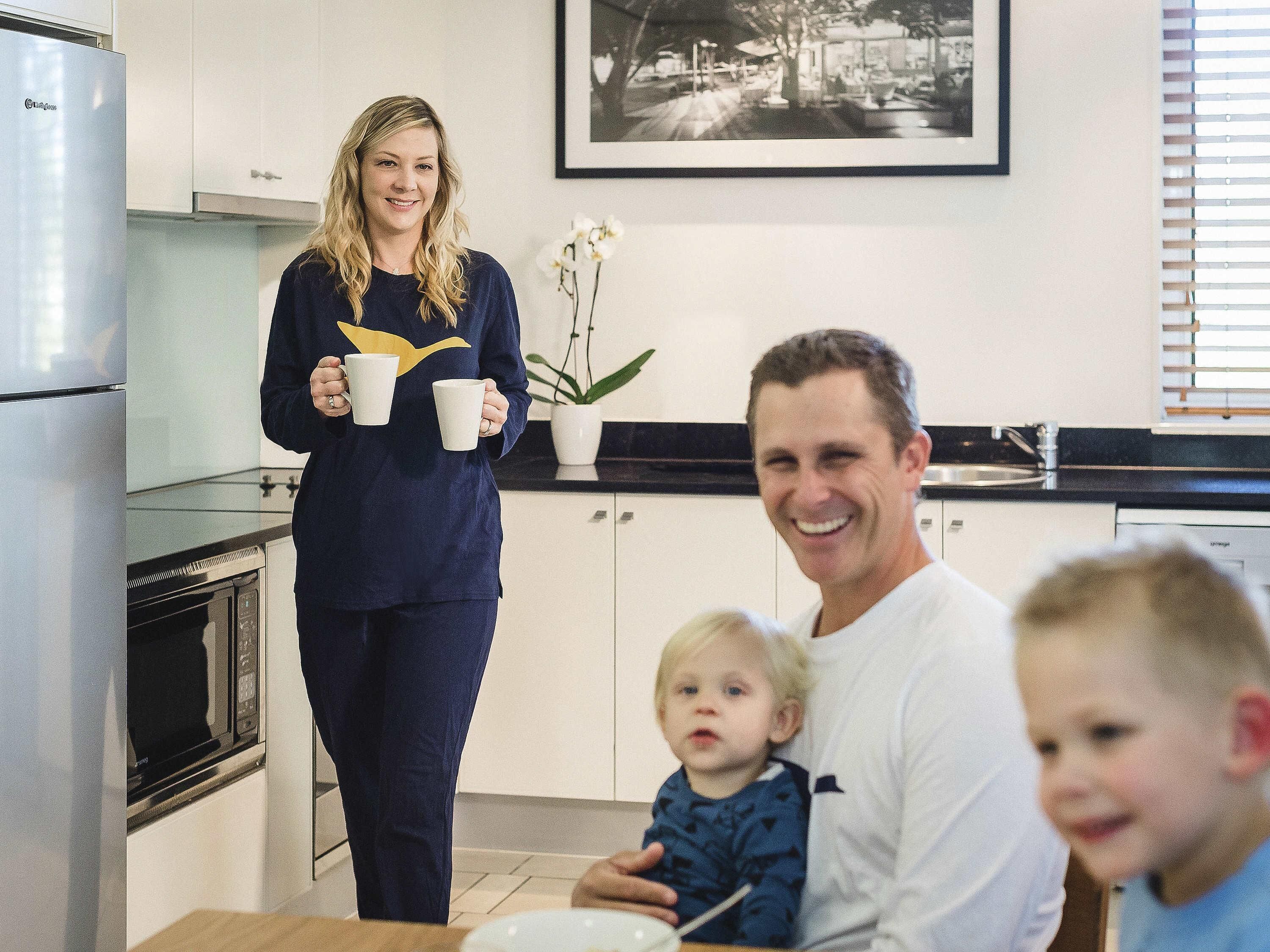 Et moderne køkken med rustfrie hårde hvidevarer, et spiseområde med et bord, og et indrammet billede på væggen.