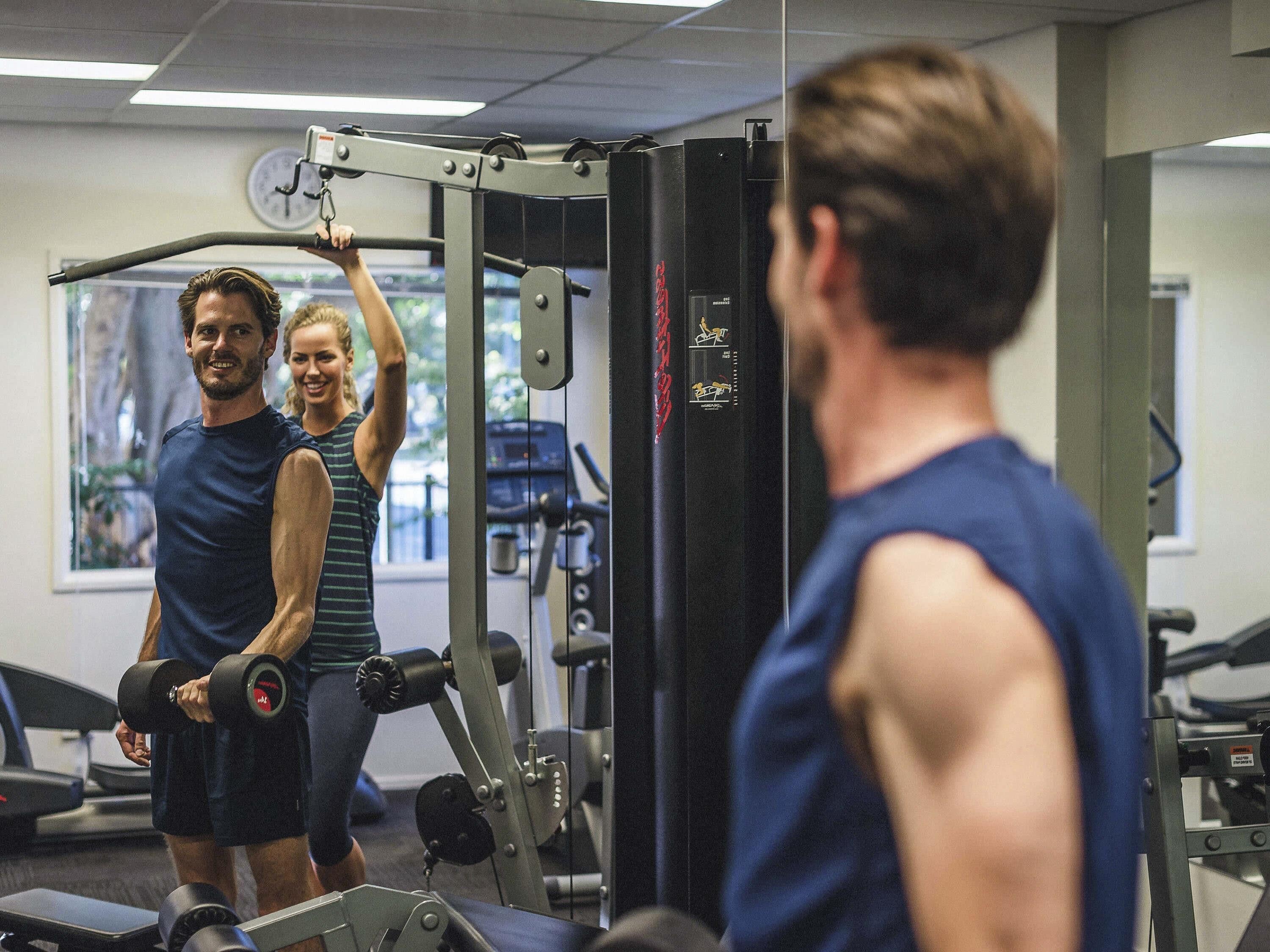 A gym with exercise equipment and a mirror.
