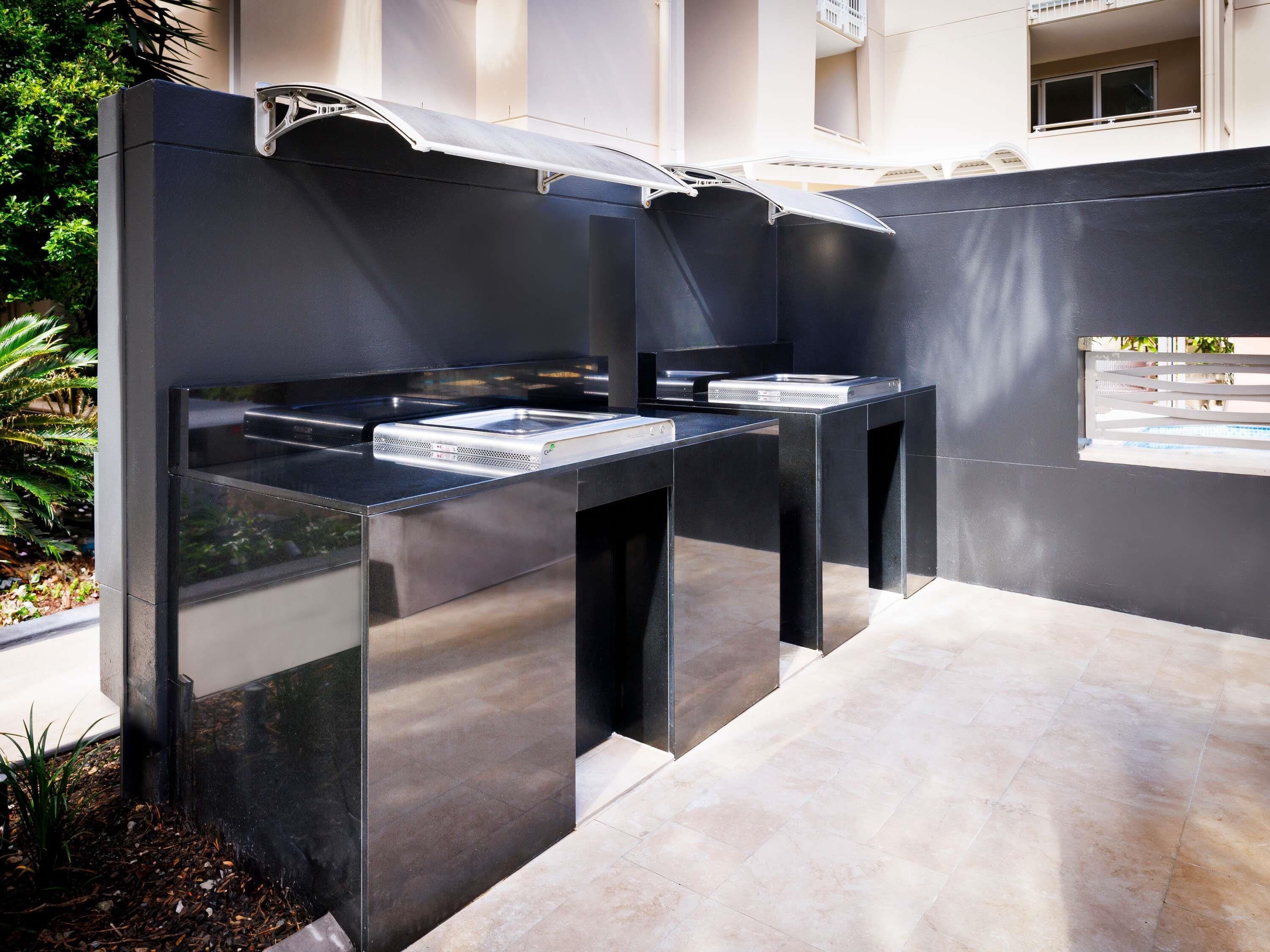 Cocina exterior con parrilla integrada y ventana con vista a una zona residencial.