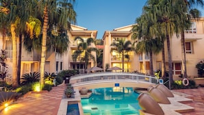 A hotel courtyard with a swimming pool, palm trees, and a bridge. - The Sebel Noosa (Noosa Heads)