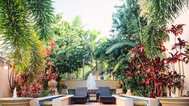 A pool area with two chairs, a small table, and a fountain. - The Sebel Noosa (Noosa Heads)
