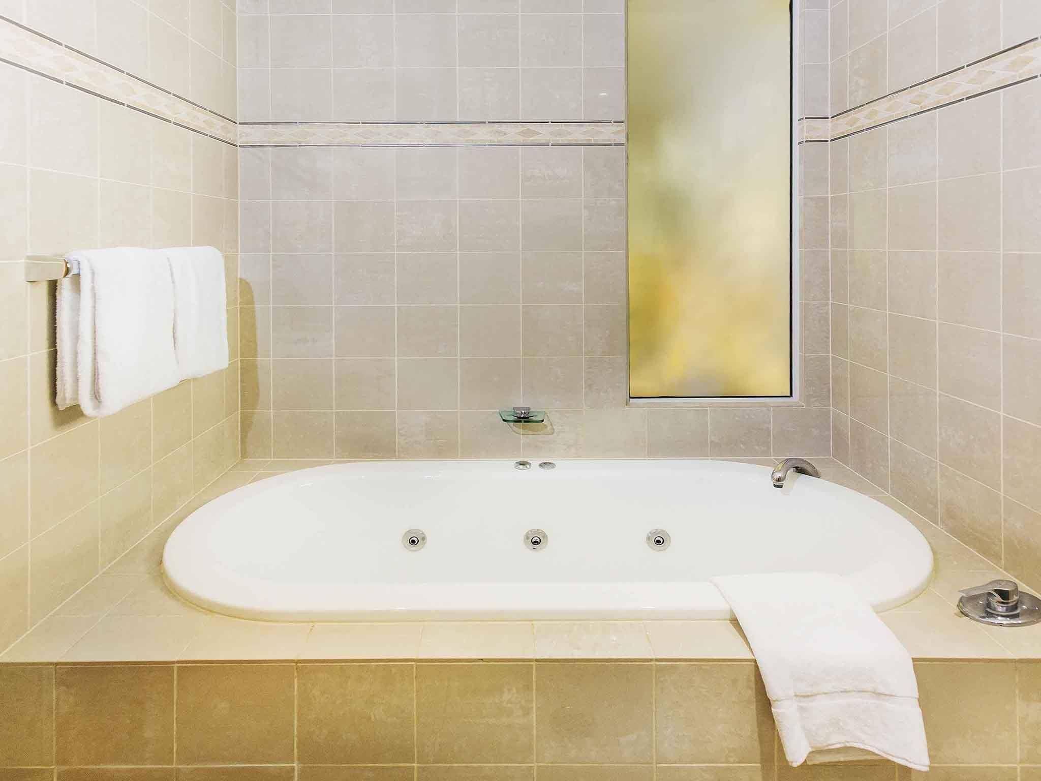 A bathroom with a freestanding bathtub, a towel rack with a towel, and a mirror.