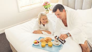 Guests can enjoy a comfortable stay in this inviting room, featuring a plush bed and a convenient breakfast tray.