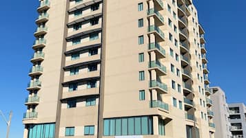 Un hôtel à plusieurs étages au design moderne, doté de balcons à chaque niveau, d’une entrée bien visible et d’une enseigne indiquant le nom « nesuto ».