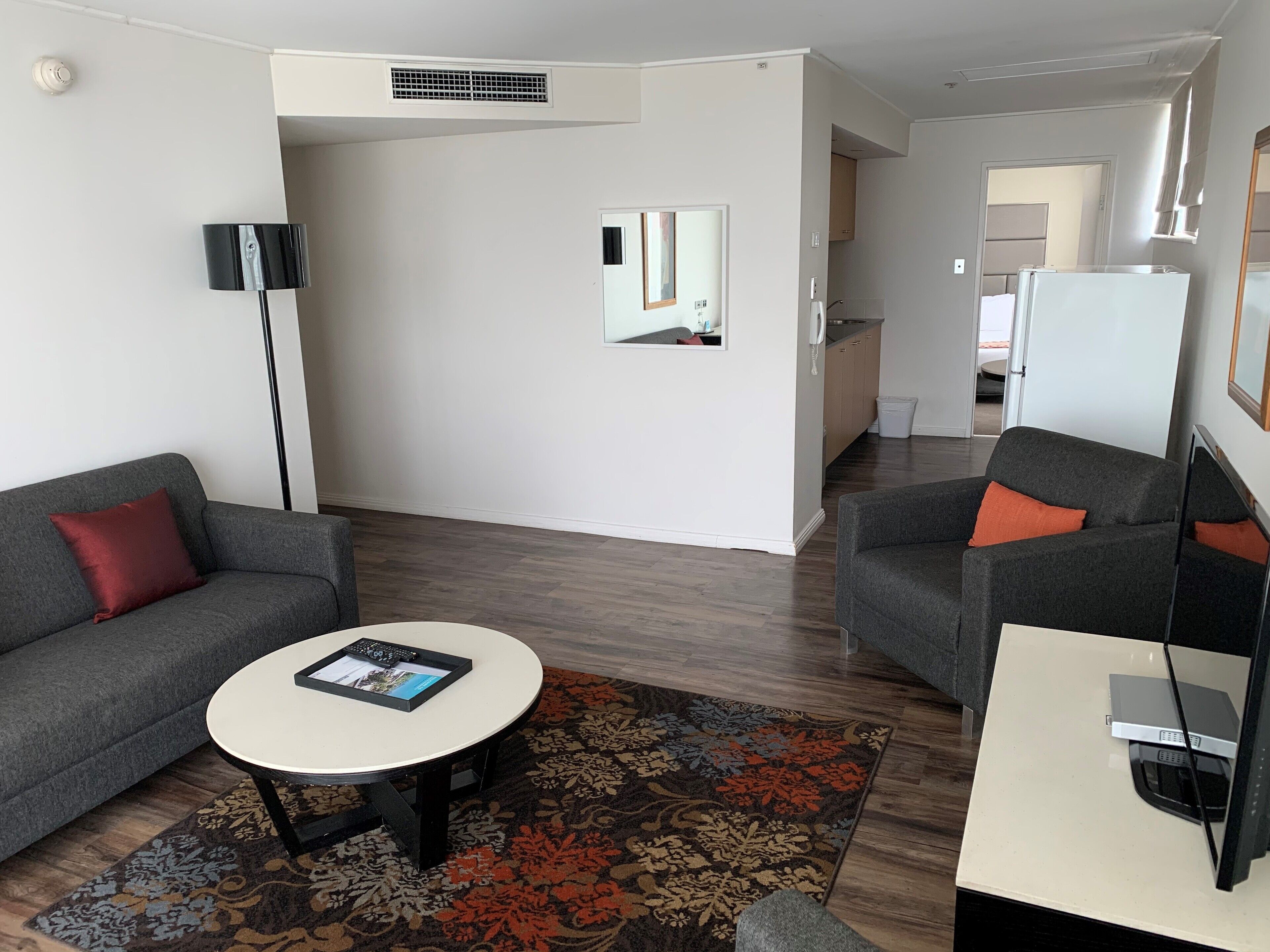 A modern living room with a grey sofa, a round coffee table, and a patterned rug.