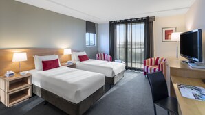 Una habitación de hotel con dos camas, un escritorio, un televisor y una silla.