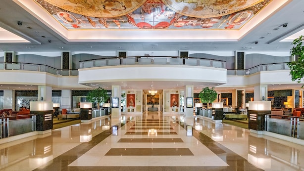 Eine geräumige Lobby mit einer zentralen Treppe, mehreren Ebenen und einem dekorativen Deckenfresko.