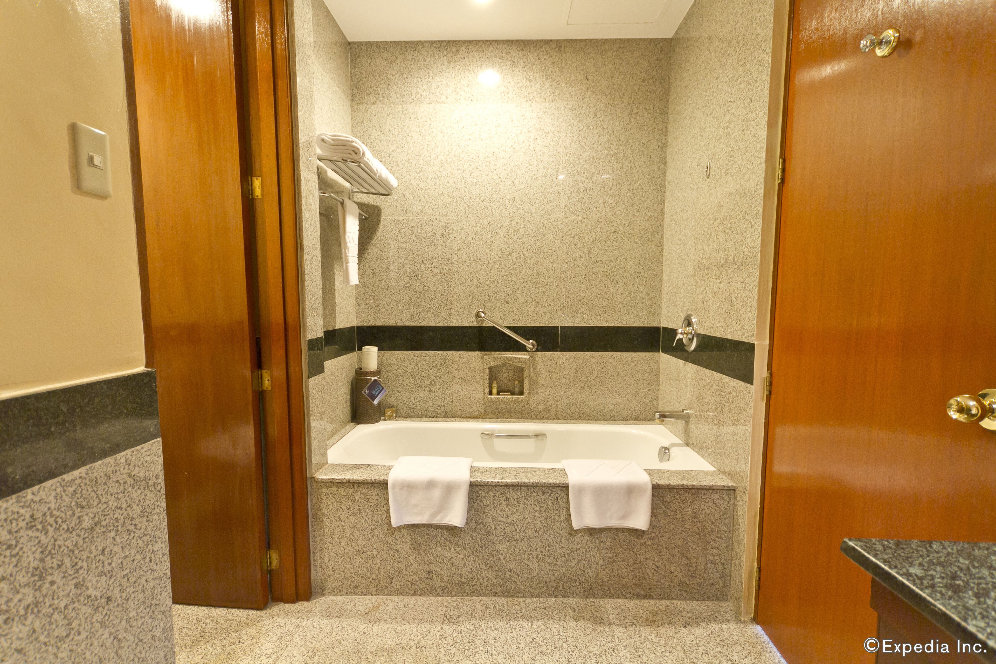 A bathroom with a bathtub, two towels, a towel rack, and a shower area.