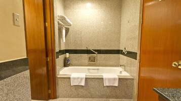 Un baño con bañera, dos toallas, un tendedero para toallas y una zona de ducha.