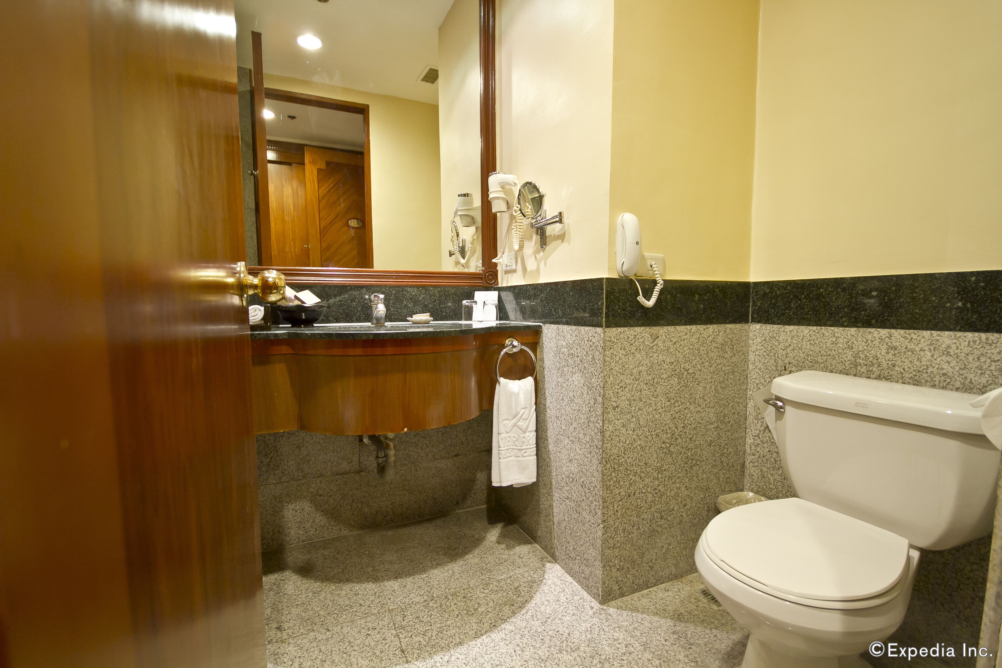 A bathroom with a toilet, sink, and mirror.