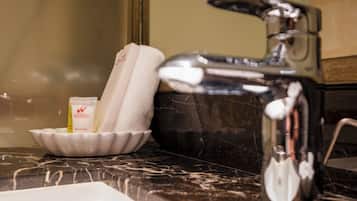 A bathroom sink with a marble countertop, a white soap dish, and a bottle of lotion.