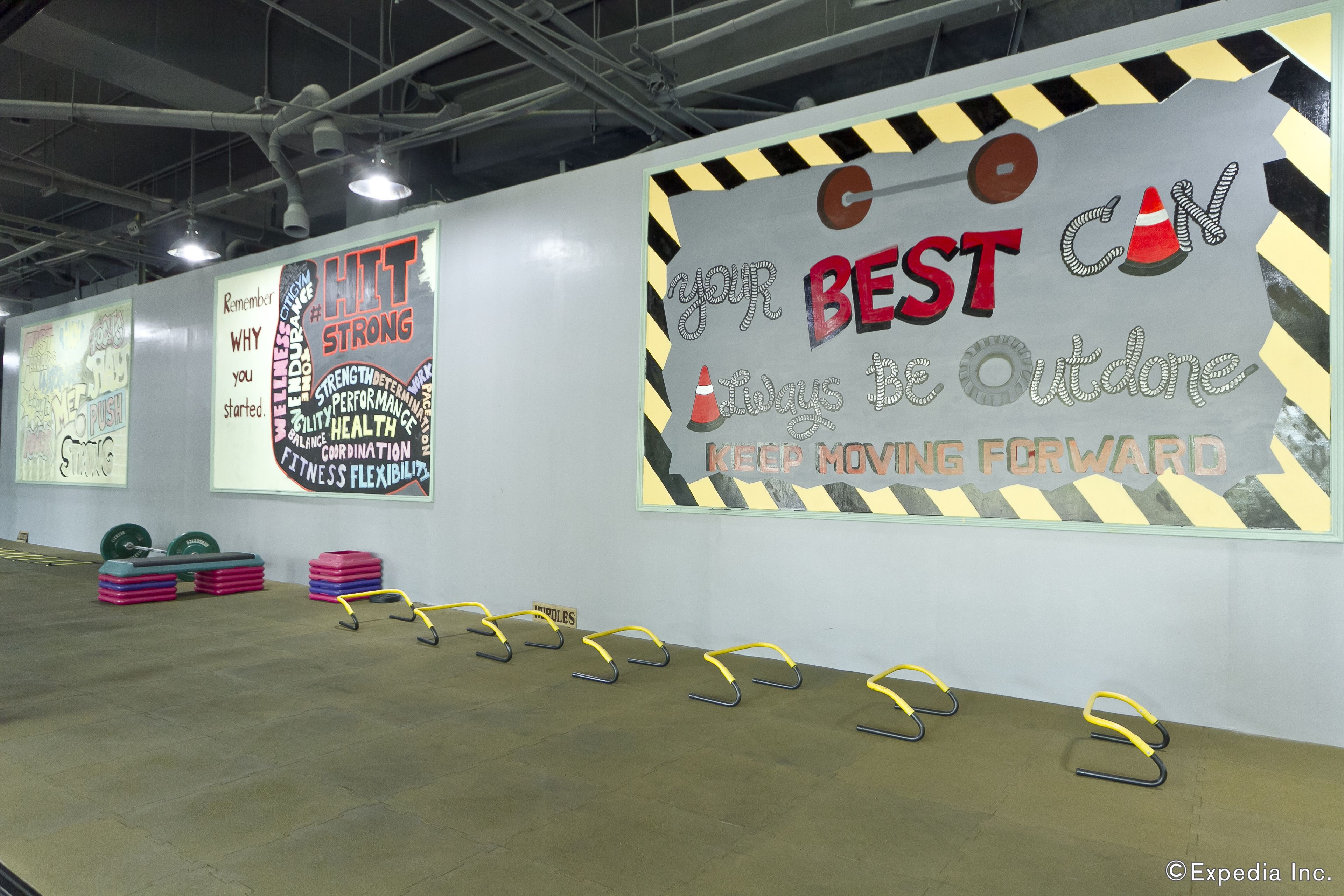 Ein Fitnessstudio mit Motivationspostern, Gewichte und Sprunghindernissen.