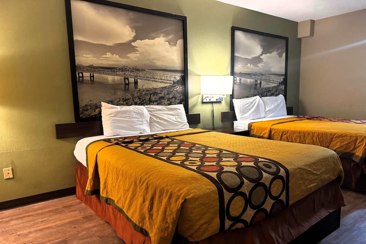 Une chambre d’hôtel avec deux lits, chacun agrémenté d’une couvre-lit à motifs, d’une tête de lit et d’une lampe fixée au mur.