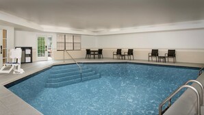 An indoor swimming pool with steps leading into the water, surrounded by chairs and a small table. - Residence Inn by Marriott Kansas City Overland Park (Overland Park)