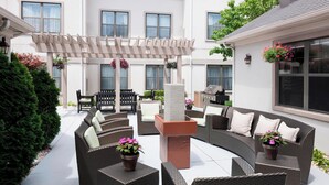A covered outdoor seating area with wicker furniture and potted plants. - Residence Inn by Marriott Kansas City Overland Park (Overland Park)