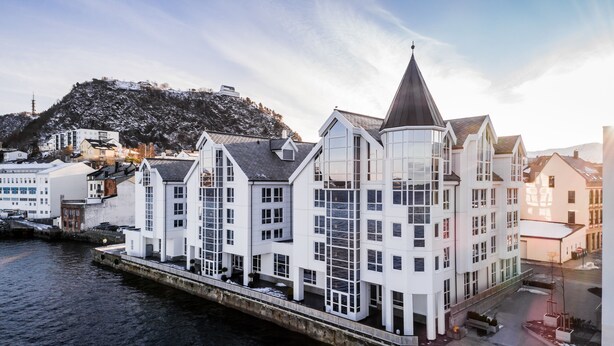 A waterfront hotel with a modern architectural design, featuring multiple floors and large windows.