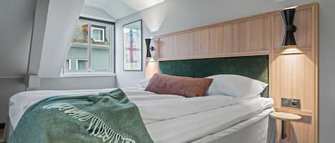 A modern bedroom with a bed, a window, and a bedside lamp.