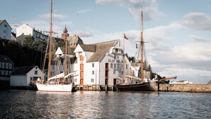 A harbor with two sailing ships docked at a white building labeled "OLUF HOLM".