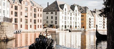 Un canal con una embarcación que transporta pasajeros, rodeado de edificios históricos con arquitectura variada.