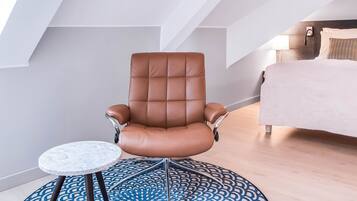 Una habitación moderna con un sillón de cuero marrón, una mesita redonda pequeña y una alfombra estampada.