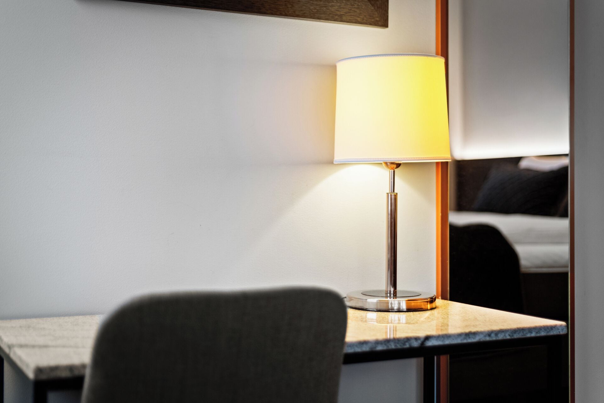 A modern lamp with a cylindrical shade on a table in a hotel room.