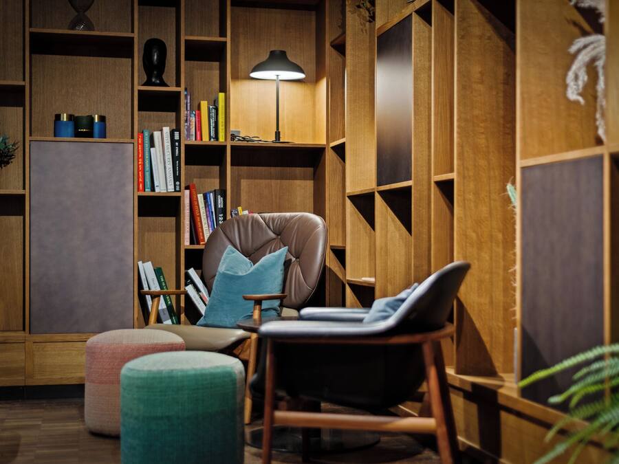 A cozy reading nook with a leather armchair, a small ottoman, and a bookshelf filled with books.
