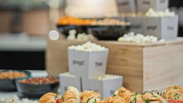 Un tavolo del buffet con croissant, pomodori e contenitori con l'etichetta contenenti cibo.