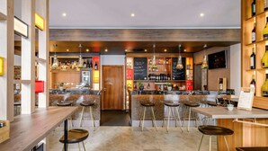 A modern bar with multiple stools, a wooden counter, and shelves stocked with bottles. - Mercure Hotel Stuttgart Gerlingen (Gerlingen)
