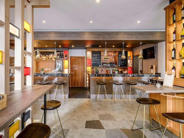Eine moderne Bar mit mehreren Hockern, einer Holztresen und Regalen voller Flaschen.