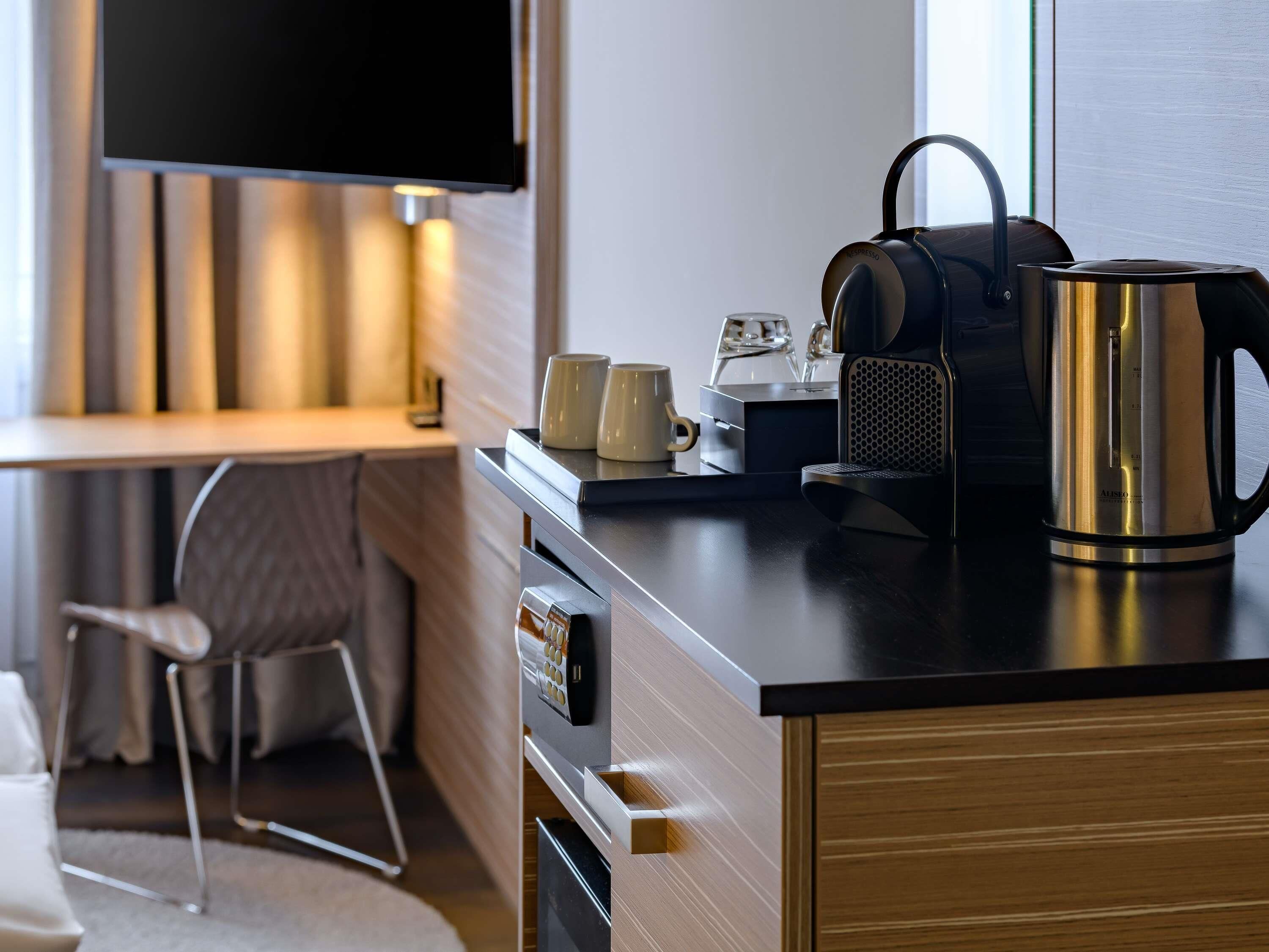A modern kitchen with a coffee maker, kettle, and two mugs on the counter.