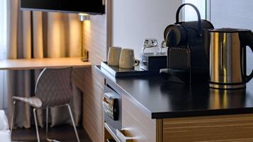 A modern kitchen with a coffee maker, kettle, and two mugs on the counter.
