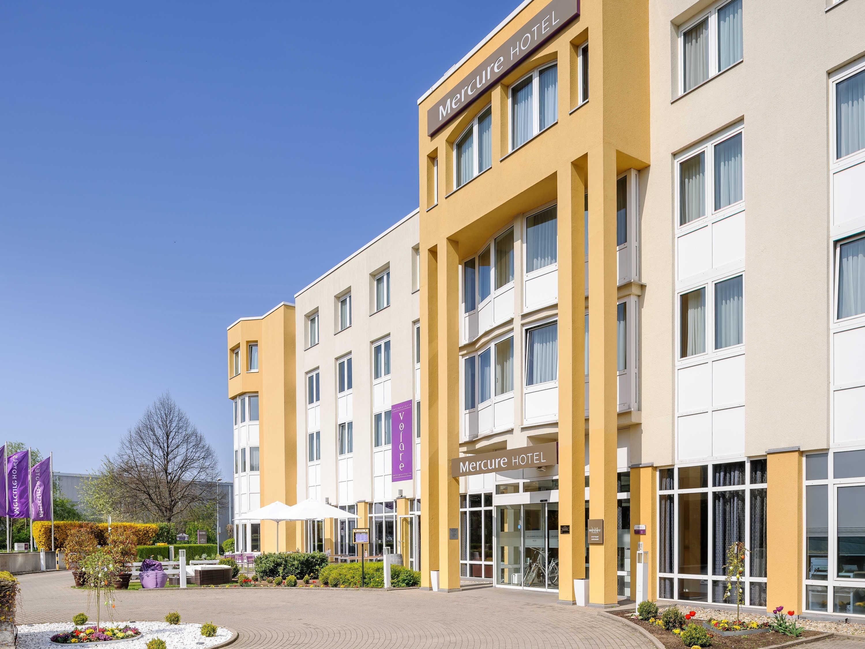 A modern hotel with a yellow facade, large windows, and a welcoming entrance.