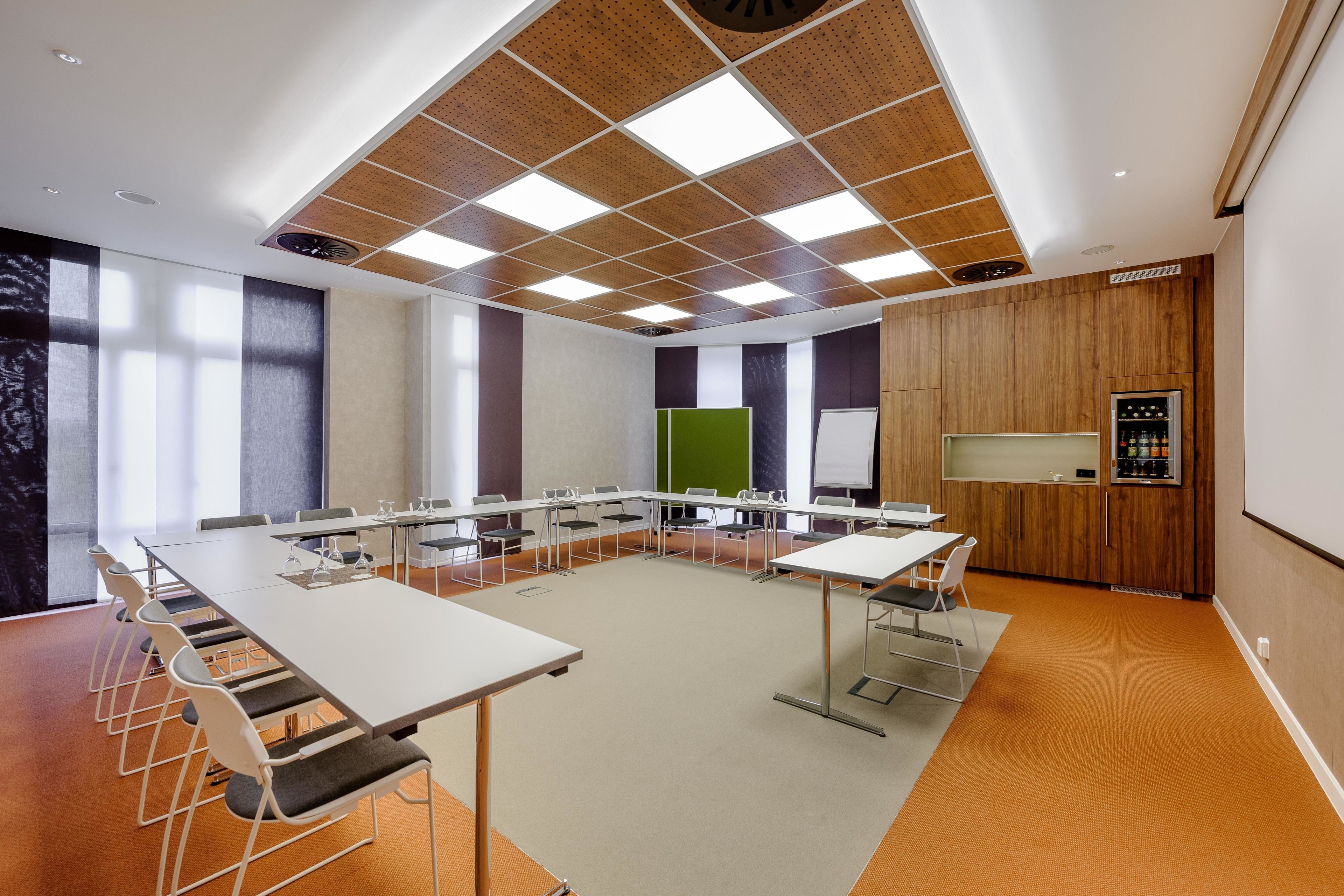 Una sala de conferencias con una larga mesa, sillas, una pantalla de proyector y una pizarra.
