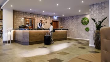Ein Hotel-Empfangsbereich mit Holztresen, einer großen Wanduhr und einer Rezeption.
