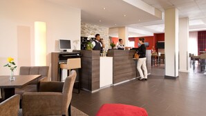 Un vestíbulo de hotel con recepción, zona de estar y comedor.