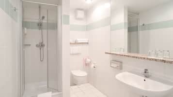 A modern bathroom with a glass-enclosed shower, a white toilet, and a sink with a mirror above it.