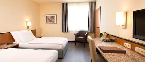 A hotel room with two beds, a desk, a chair, a television, and a window with curtains.