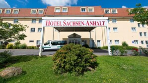 Un hotel llamado "Hotel Sachsen-Anhalt" con techo de tejas rojas, varias ventanas y una entrada cubierta.