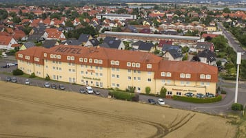 Un hotel con diversi piani, un parcheggio e vista sul quartiere residenziale circostante.