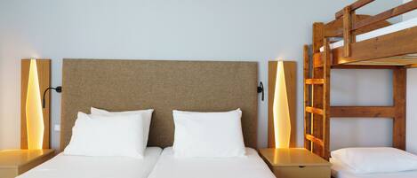 A double bed with a wooden headboard, two bedside tables, and a wooden bunk bed to the right.