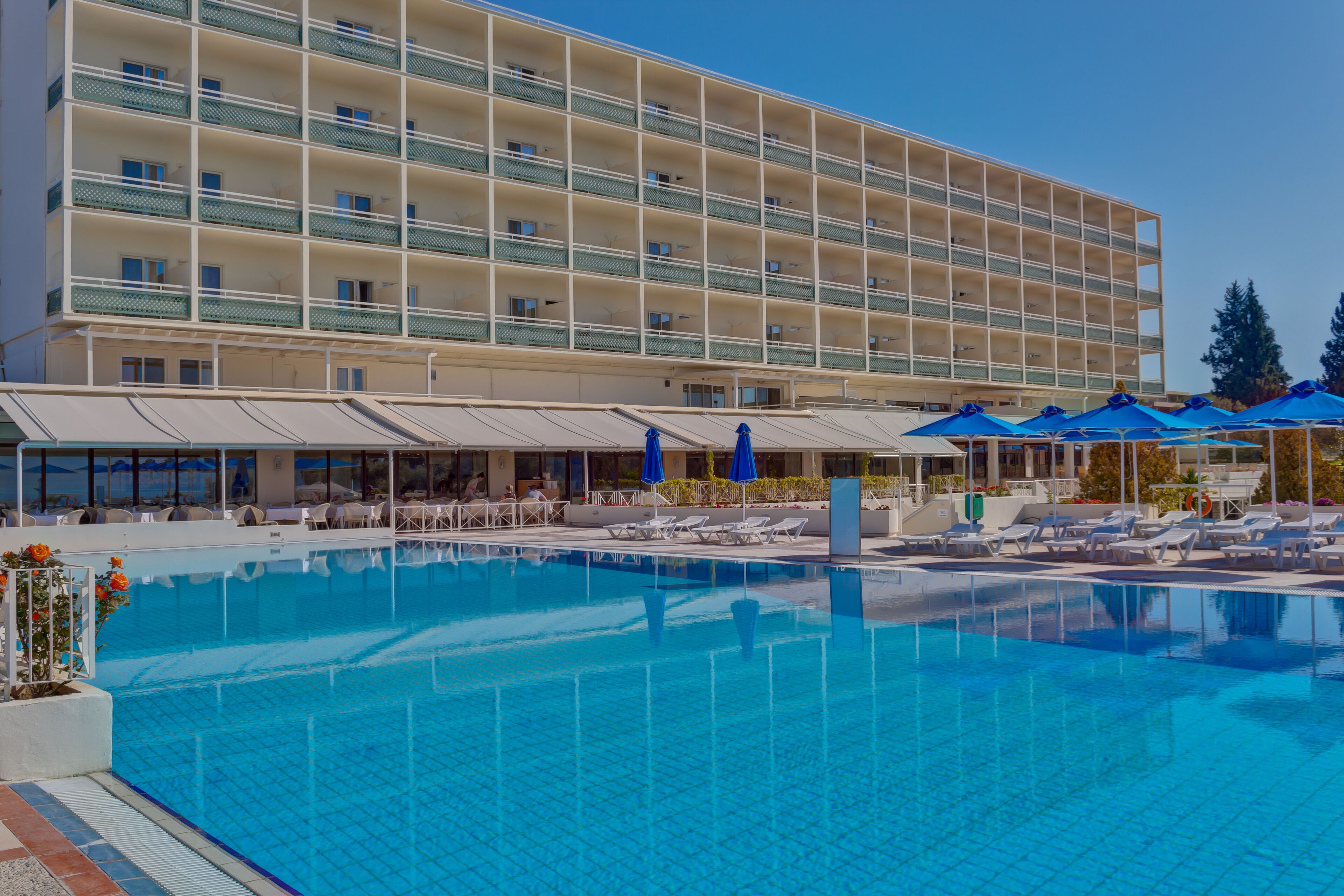 Ein Hotel mit einem großen Schwimmbad, Liegestühlen und Sonnenschirmen.