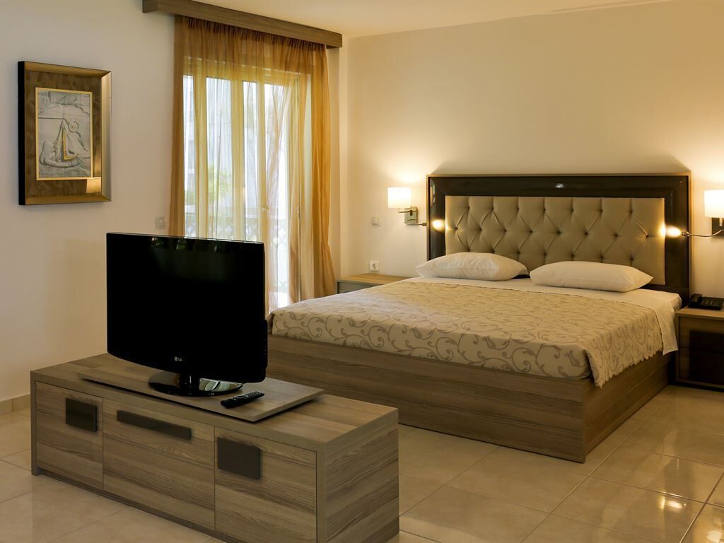 Ein Hotelzimmer mit einem Bett, einem Fernseher auf einer Holzkommode und einem Bild an der Wand.