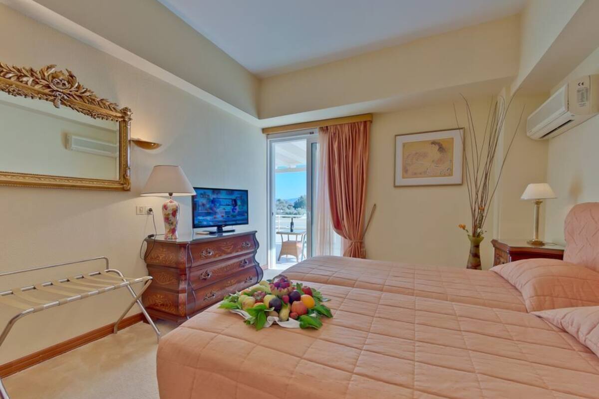 A hotel room with a bed, a dresser, a television, a window with curtains, and a painting on the wall.